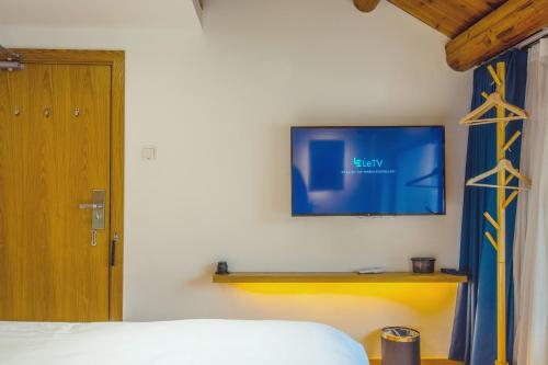 a bedroom with a bed and a tv on the wall at Han Xuan Boutique Hostel in Hangzhou