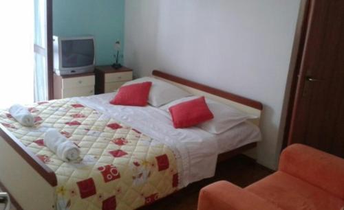 um quarto com uma cama com almofadas vermelhas e uma cadeira em Apartment Marik em Jelsa