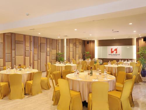 a banquet hall with tables and chairs and a screen at Swiss-Belhotel Makassar in Makassar