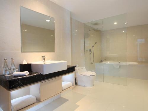 y baño con lavabo, aseo y ducha. en Swiss-Belhotel Makassar en Makassar