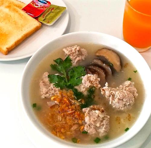 a bowl of soup with bread and a glass of orange juice at Hotel Chuan Chom The High Resort Saraburi - SHA Plus in Sara Buri