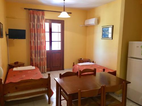 a room with two beds and a table and a refrigerator at Argo Apartments near Nafplio in Néa Kíos