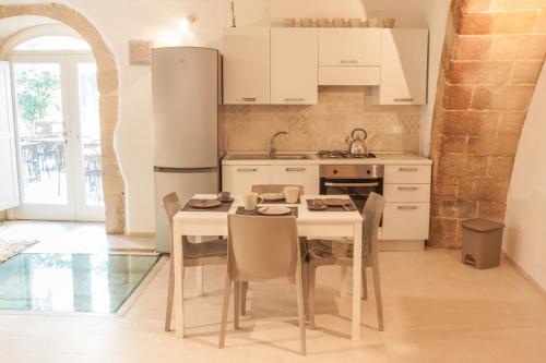 シラクーサにあるDOMUS 1333 al DUOMOの白いキャビネット、テーブルと椅子付きのキッチンが備わります。