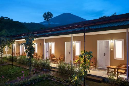 a house with chairs and tables and mountains in the background at Rinjani Garden by ecommerceloka in Sembalun Lawang