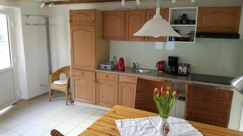 eine Küche mit Holzschränken und einem Tisch mit einer Vase aus Blumen in der Unterkunft Ferienwohnung Alwind 5 in Lindau