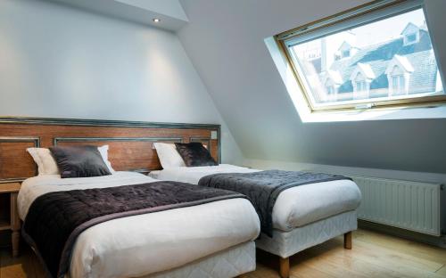 two beds in a room with a window at Hôtel Du Brésil in Paris