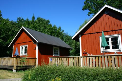 a red house with a black roof and a fence at Dragsö Camping & Stugby in Karlskrona