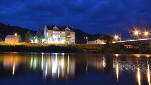 a building on the shore of a river at night at Motel New Sanatron in Bosanski Novi