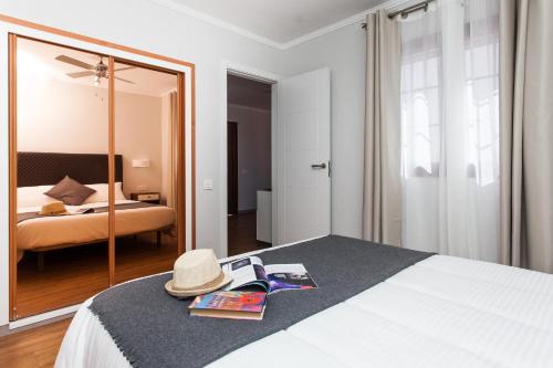 a bedroom with a bed with a hat and a mirror at Apartamentos Villa Florida in Caleta De Fuste
