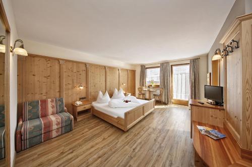 um quarto de hotel com uma cama e uma televisão em Hotel Tschantnaihof em Collepietra