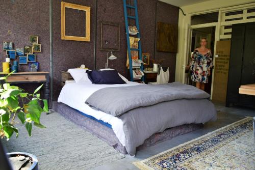 Un dormitorio con una cama y una mujer parada en una puerta en Un Autre Monde, en Saint-Claude