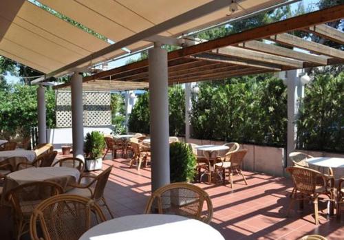 un patio al aire libre con mesas y sillas y una pérgola de madera en Miami Hotel en Mati