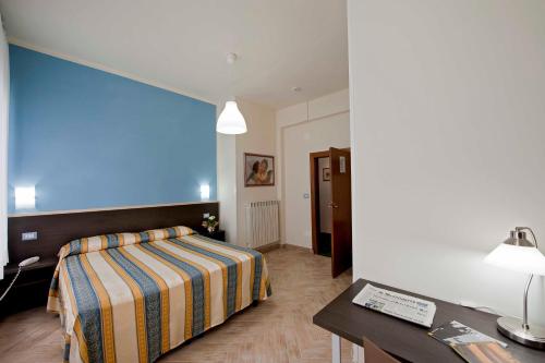 a bedroom with a bed and a desk and a table at Hotel Moderno in Siena