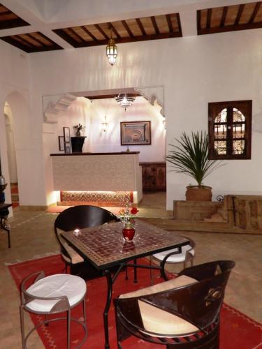 sala de estar con mesa, sillas y chimenea en Riad Carina, en Marrakech