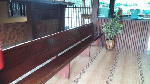 a wooden bench in a building with a potted plant at Dominique Hotel in Ouro Preto dʼOeste