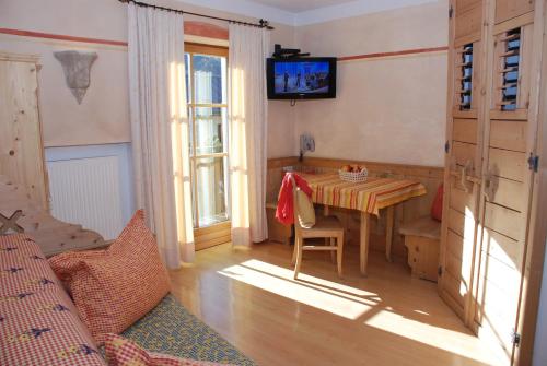 Zimmer mit einem Tisch und einem TV an der Wand in der Unterkunft Piccolohotel Tempele Residence in Innichen