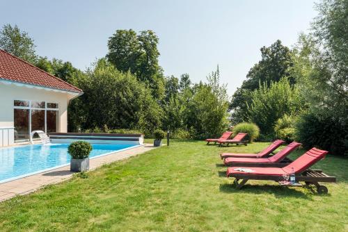 a row of red lounge chairs next to a swimming pool at Best Western Plus Parkhotel Maximilian Ottobeuren in Ottobeuren