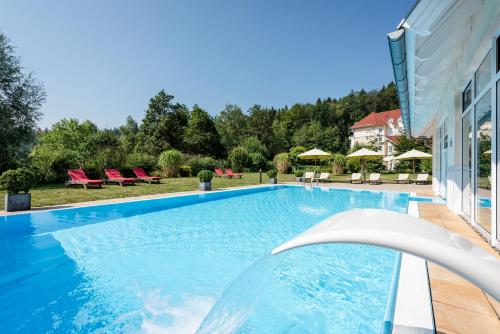 - une piscine avec des chaises et une maison dans l'établissement Best Western Plus Parkhotel Maximilian Ottobeuren, à Ottobeuren