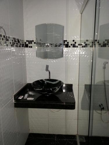 a bathroom with a sink and a glass shower at Shopping Motel Santa Maria do Pará in São Jorge