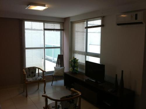 sala de estar con 3 ventanas y TV de pantalla plana en Apartamento Orla do Cabo Branco, en João Pessoa