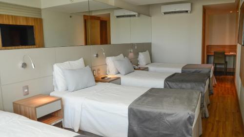 a hotel room with three beds and a mirror at Hotel Atlântico Travel Copacabana in Rio de Janeiro