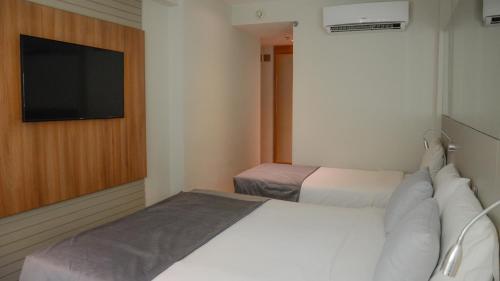 a bedroom with two beds and a flat screen tv at Hotel Atlântico Travel Copacabana in Rio de Janeiro