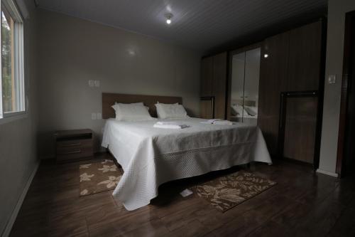 a bedroom with a large bed with white sheets at O Rancho in Palmeira das Missões