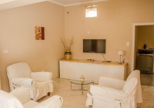 sala de estar con sillas blancas y TV de pantalla plana en Casa Las Parras en San Rafael