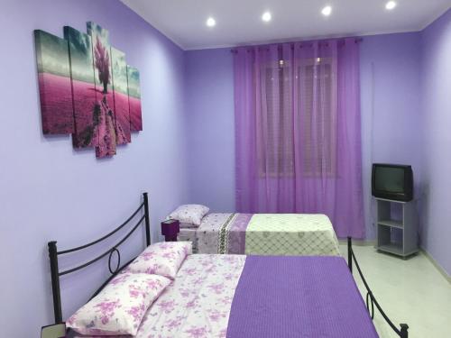 a purple bedroom with a bed and a tv at La Casa di Simone in Avola