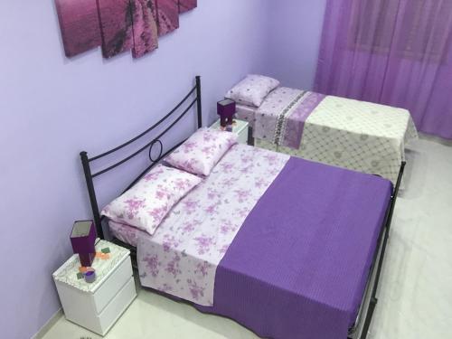 a bedroom with two beds with purple and white sheets at La Casa di Simone in Avola