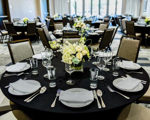 a black table with plates and glasses and flowers on it at Cambria Hotel McAllen Convention Center in McAllen