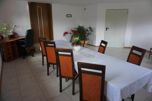 a dining room with a white table and chairs at Gościniec Klejnot in Borowo