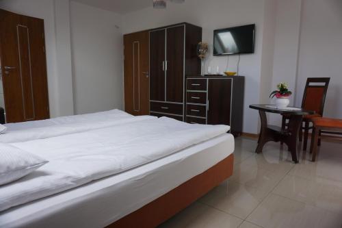 a bedroom with a bed and a table with a chair at Gościniec Klejnot in Borowo