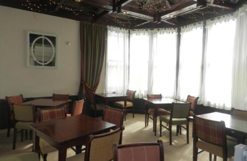 a dining room with tables and chairs and windows at Albert Hotel in Peterhead