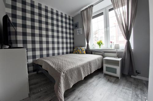 a bedroom with a bed and a checkered wall at Euro Apartments Piwna in Gdańsk