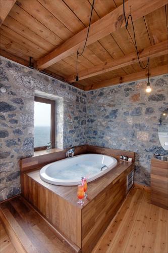 a large bath tub in a room with a window at Aegila Boutique Hotel in Éxo Nímfion