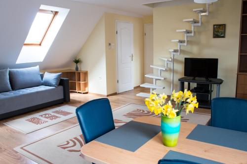 a living room with a couch and a table with yellow flowers at Titán Apartman in Gyula