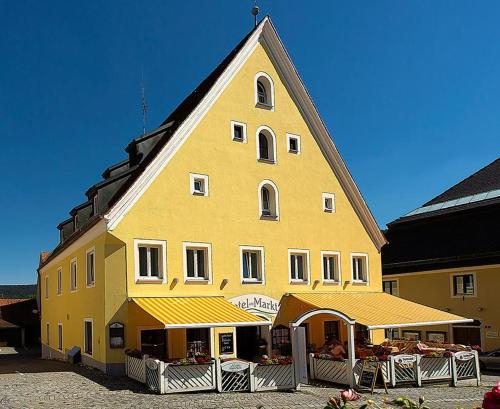 ein großes gelbes Gebäude mit Tischen davor in der Unterkunft Hotel am Markt in Greding