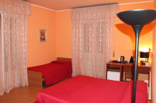 a bedroom with two beds and a desk and curtains at Albergo Paradiso in Maccagno con Pino e Veddasca
