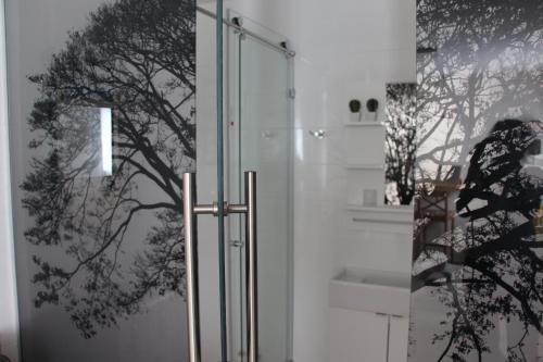 a shower with a glass door with a tree mural at DesertB in Giv'ot Bar