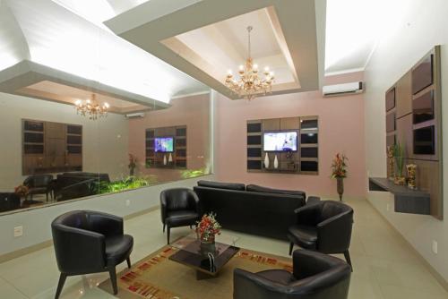 a waiting room with black leather chairs and a tv at Augustu's Hotel in Altamira