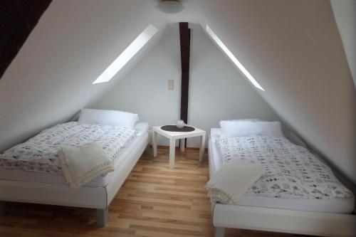 デュッセルドルフにあるフルークハーフェンアパートメント スカイビューの屋根裏のベッドルーム(ベッド2台、テーブル付)