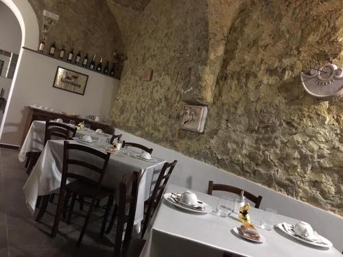 a dining room with white tables and chairs and a stone wall at Tenuta Ferrara in Altavilla Silentina
