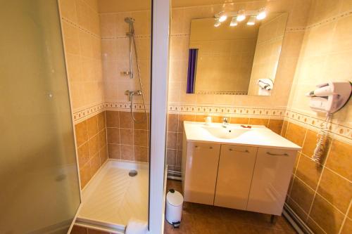 ein Bad mit einer Dusche, einem Waschbecken und einem Spiegel in der Unterkunft Grand Hotel De France in Meyrueis