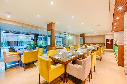 a dining room with yellow chairs and tables at Hotel Arizona Suites Cúcuta in Cúcuta