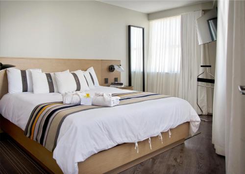 una camera da letto con un grande letto con coperte e cuscini bianchi di Casa Grande Suites a La Paz