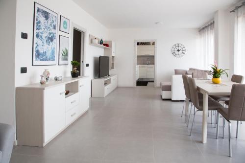 a white living room with a table and a dining room at La terrazza sul lago in Pergine Valsugana