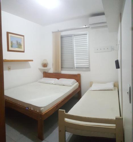 two beds in a small room with a window at Apto Portal das Palmeiras in Ubatuba