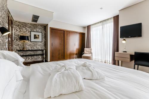 a hotel room with a white bed with two towels at Hotel Villa Batalha in Batalha