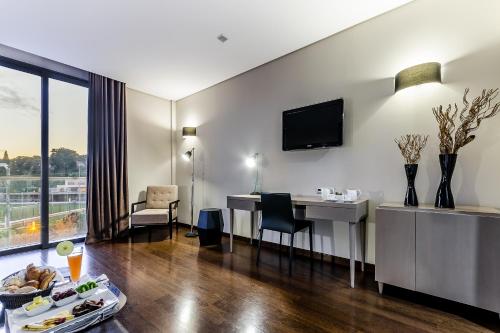 a hotel room with a table and a desk and a room at Hotel Villa Batalha in Batalha